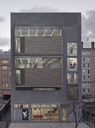 3 story modern building with grey panels, stone cladding and large windows