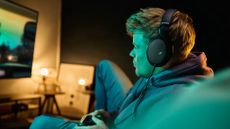 A young man playing a video game while wearing Sennheiser HD 550 headphones