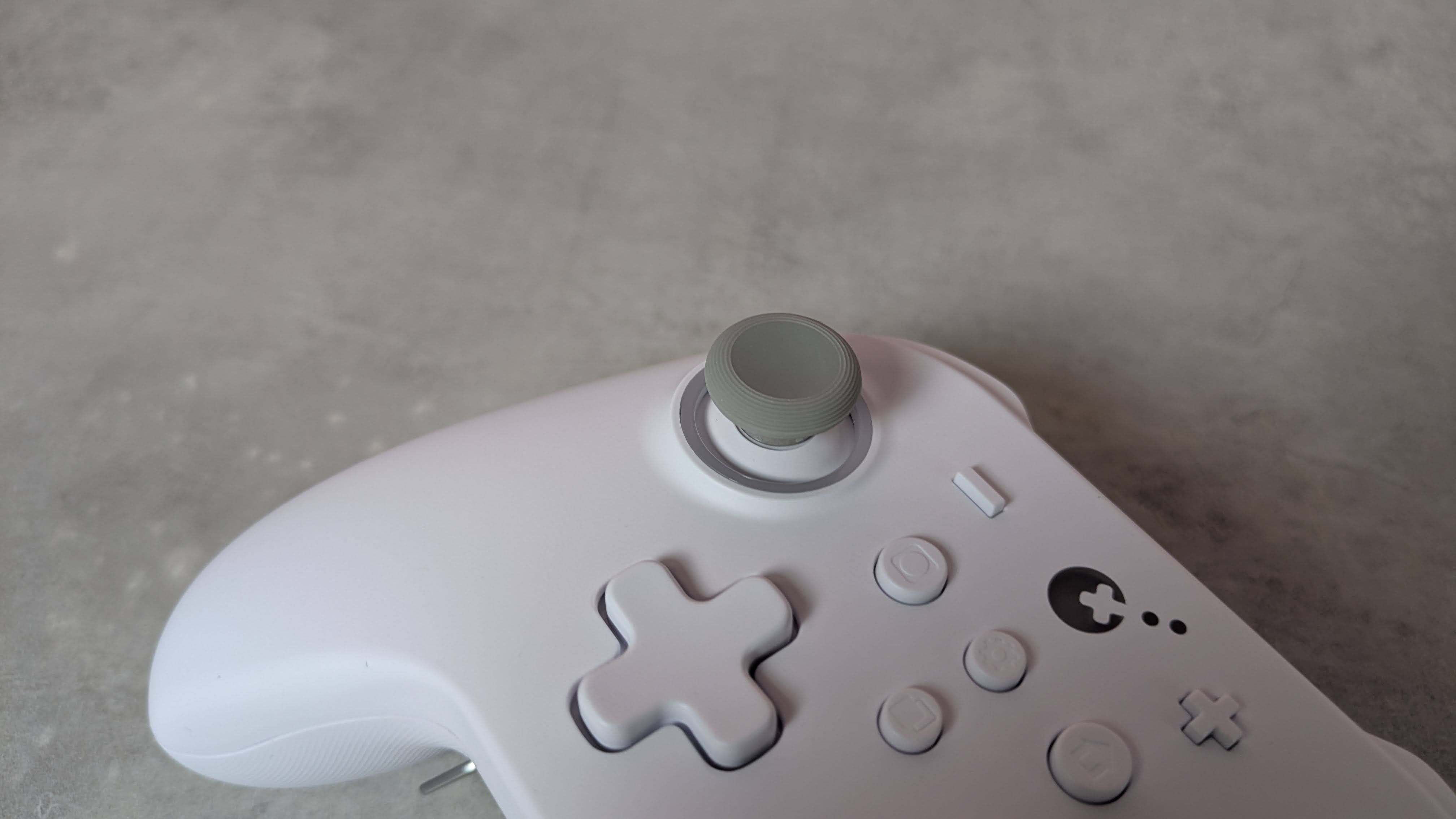 Close-up of left analog stick on GuliKit KK3 Max, on a grey desk
