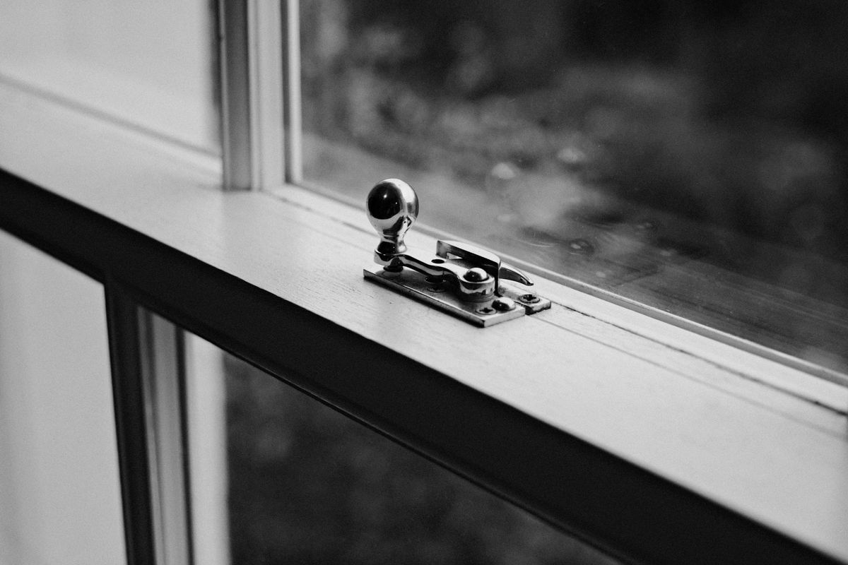 Black-and-white close-up of a metal window latch on a sill