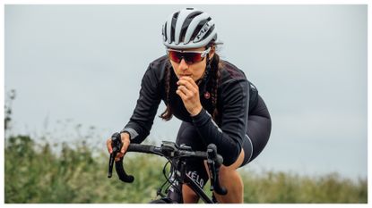 A female cyclist eating an energy bar as she rides
