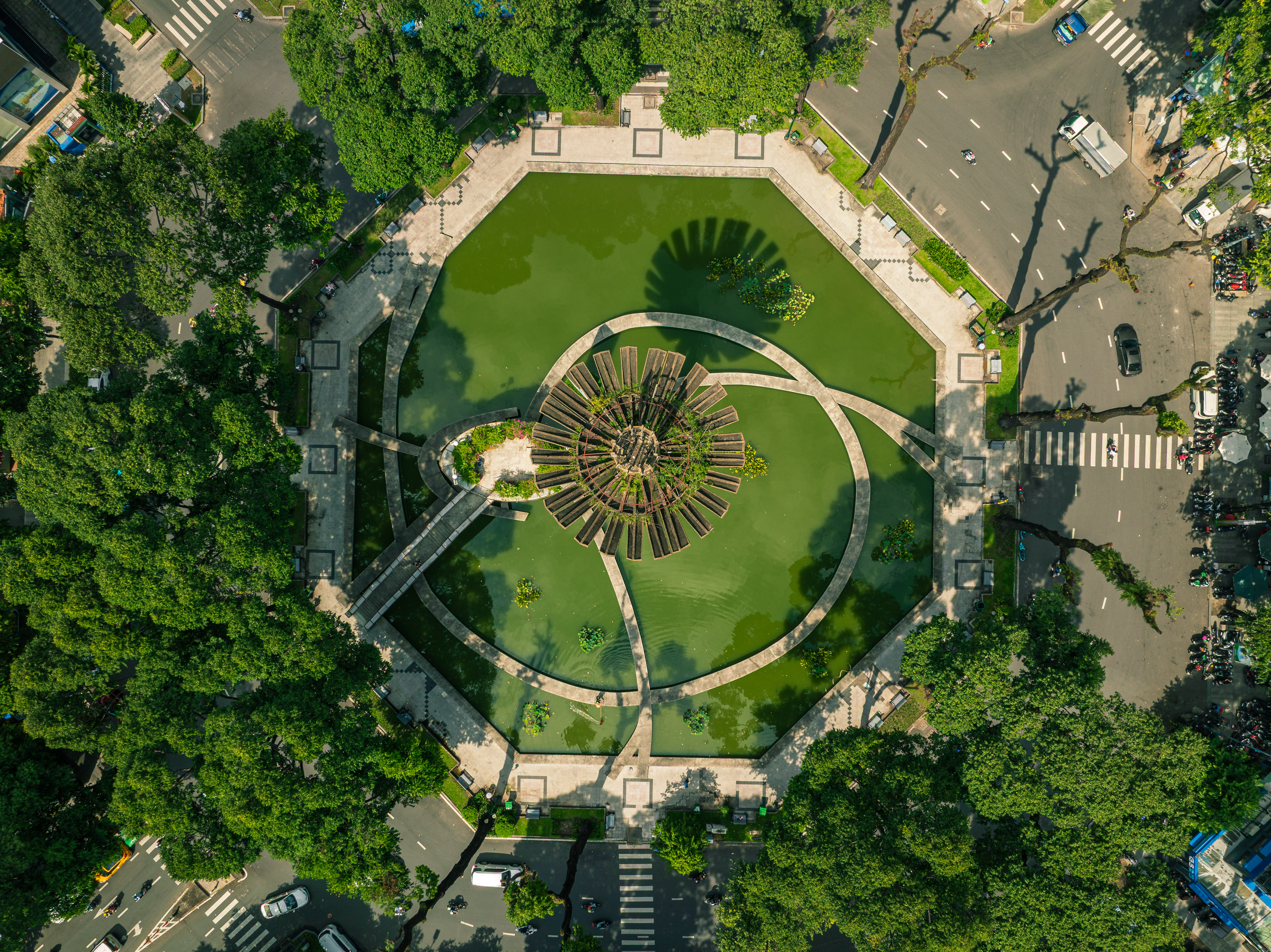 An aerial view of a green lung in a city, expanding in a polygonal shape in the heart of a roundabout.