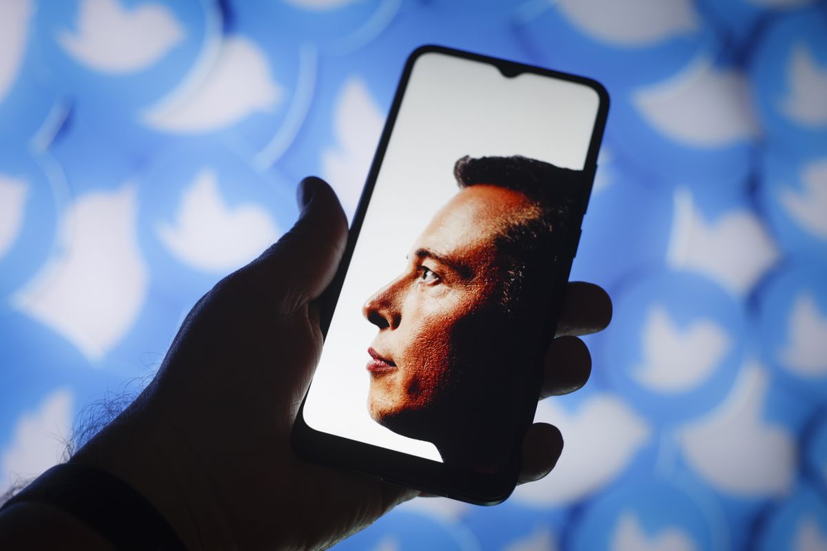 Elon Musk photo on phone with Twitter logos in background