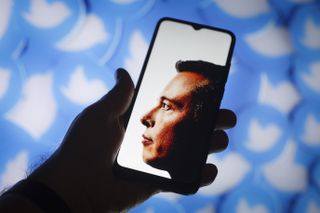 Elon Musk photo on phone with Twitter logos in background