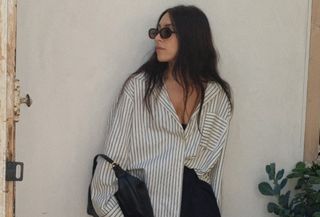 @laurencaruso_ wearing a striped button-down shirt and black skirt.