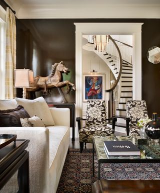 living room with glossy dark brown walls, white trim and white sofa with statement decor