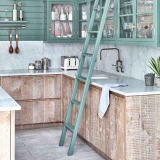 Kitchen with white marble wall and green cupboards and green ladder