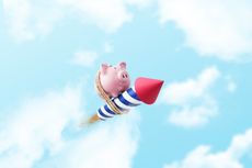 Piggy bank tied to a rocket flying through the air