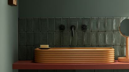 Small bathroom tile ideas A Bert and May bathroom featuring a terracotta sink and small bathroom tiles in dark green