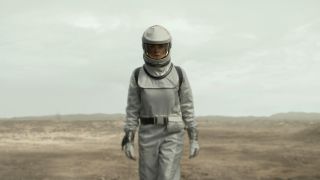 Rebecca Ferguson stands in a wasteland in a sealed encounter suit in Silo Season 2.