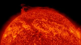 A satellite image of the sun shows a looping filament of plasma breaking off of the sun and forming a vortex around the star's north pole.