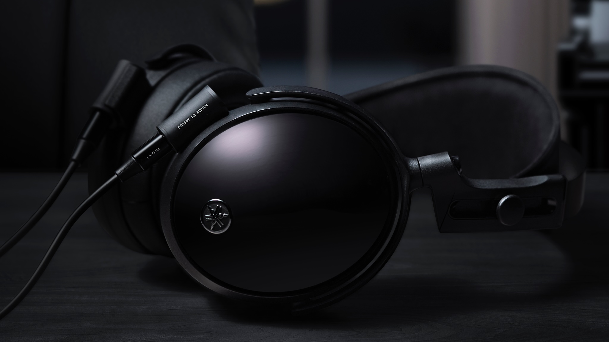 A pair of Yamaha YH-C3000 headphones on a dark coloured desk