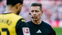 A soccer referee wearing an ear-mounted communications headset speaking directly to a player on the field. JPG
