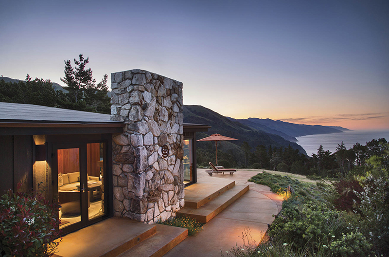 Stone and wood mid-century building on a cliff overlooking the ocean