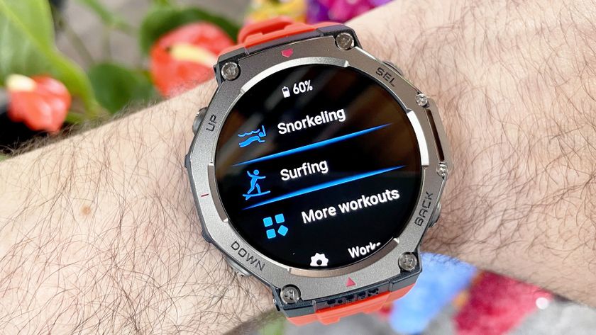 The Amazfit T-Rex 3 shown close-up on a user&#039;s wrist with the snorkeling and surfing workout tracking modes displayed; colorful flowers are out of focus in the background