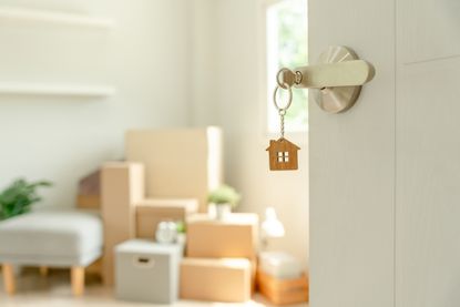 Interior of home with front door open and key chain in the shape of a house hanging from the lock.