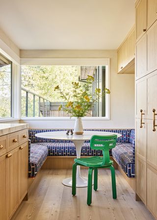 kitchen with banquette seating in patterned fabric and a green chair