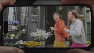 Dos manos sujetando un iPhone que muestra a dos personas corriendo