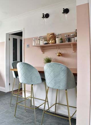 wooden breakfast bar shelf on pink walls with blue and gold stools