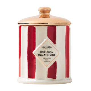 A red and white striped ceramic candle with a brass lid