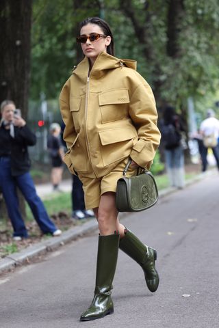 a model wears a cargo gucci jacket boots and the gucci blondie bag while walking around at milan fashion week