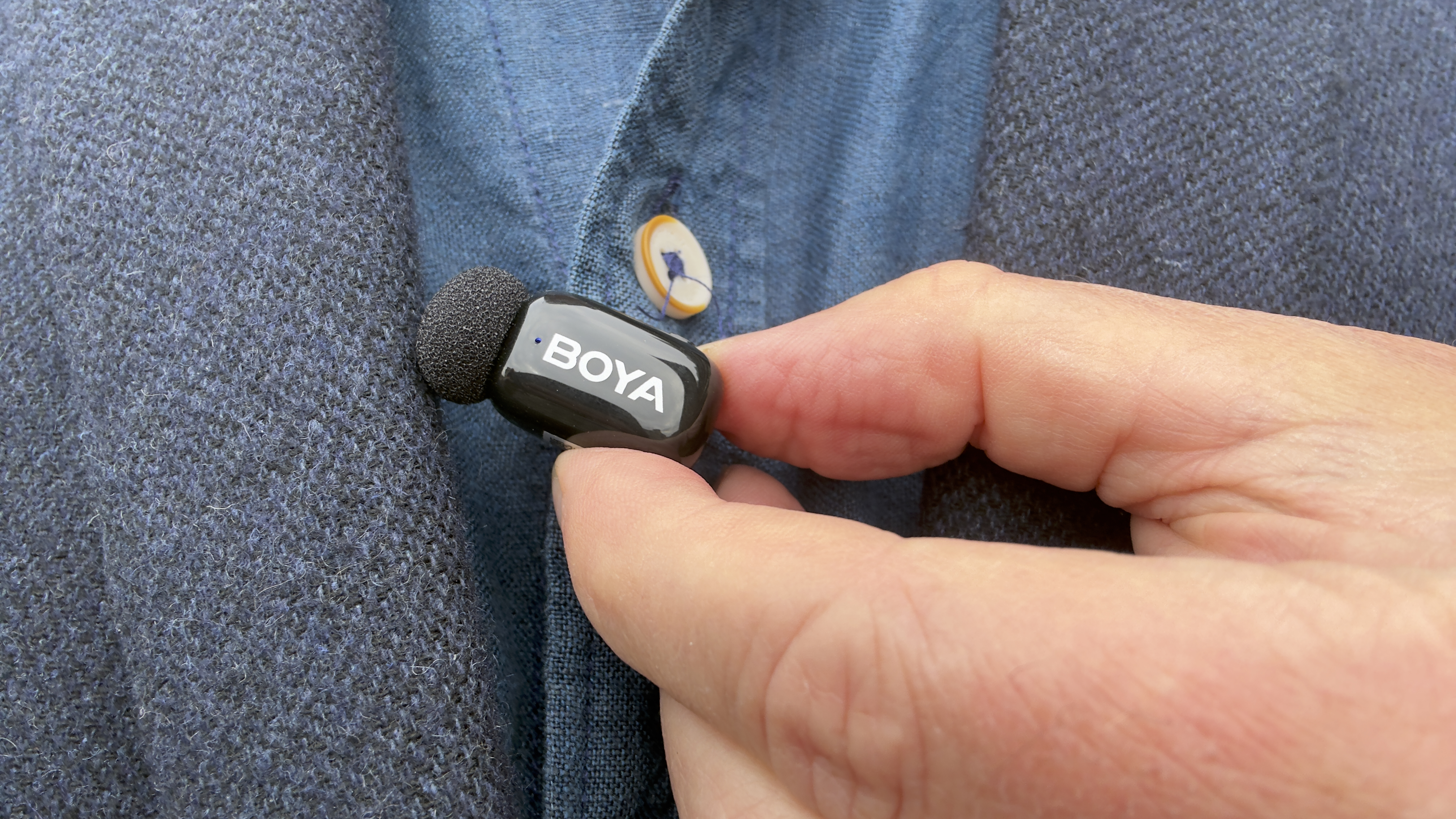 Close-up of the Boya mini 2 microphone clipped to a shirt. The status light shines blue
