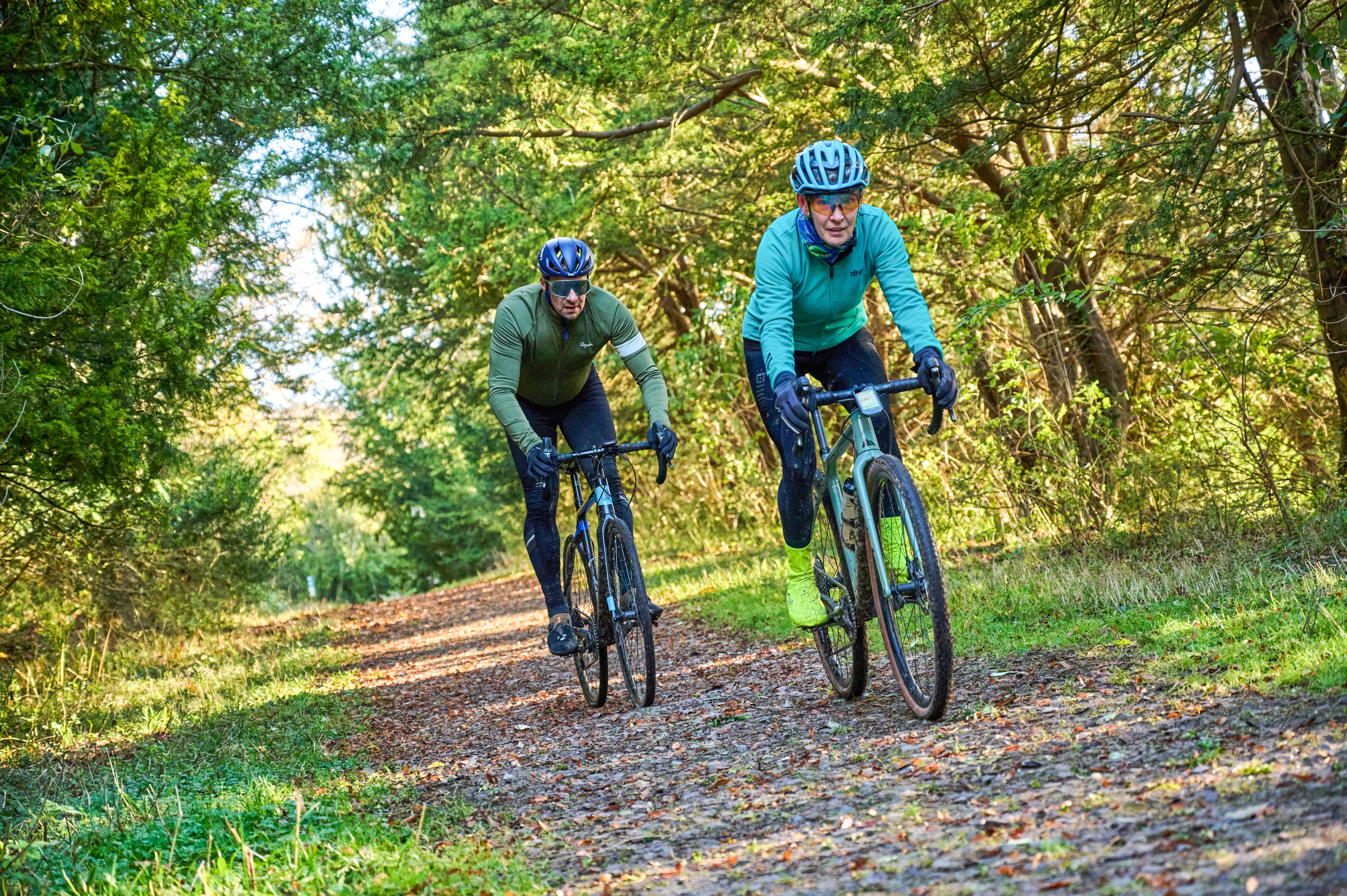 Female and make cyclist ride along a woodland path