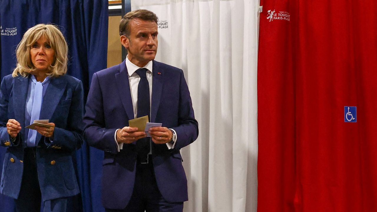 Emmanuel Macron and his wife Brigitte exit a polling booth after casting their ballot for the European Parliament election