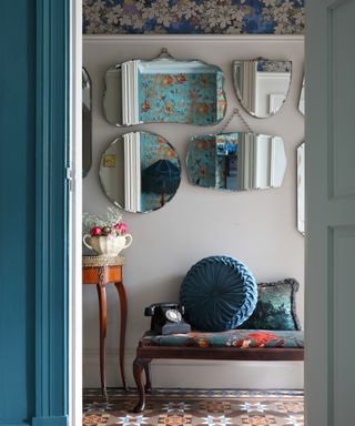 hallway with Edwardian floor tiles, display of vintage mirrors and wallpaper above picture rail