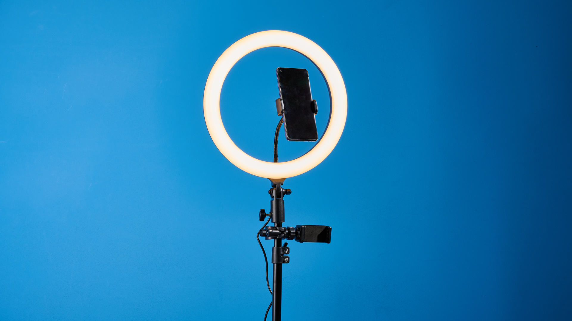 Godox 12-inch ring light photographed in front of a blue background with an iPhone on the phone mount. 