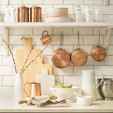 Detail of a kitchen worktop with white brick tiles and copper accessories