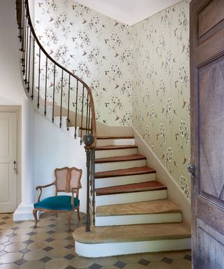 wooden stairwell in floral wallpaper, wooden lounge chair on tiled flooring