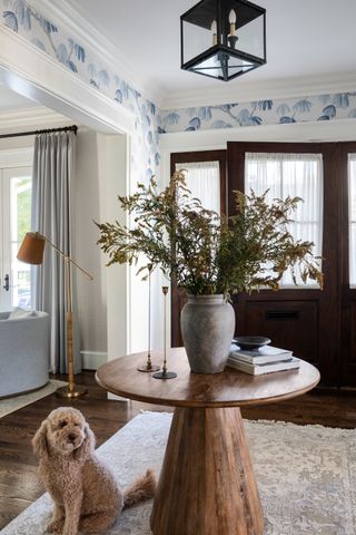 An entryway with a round table with a vase of foliage