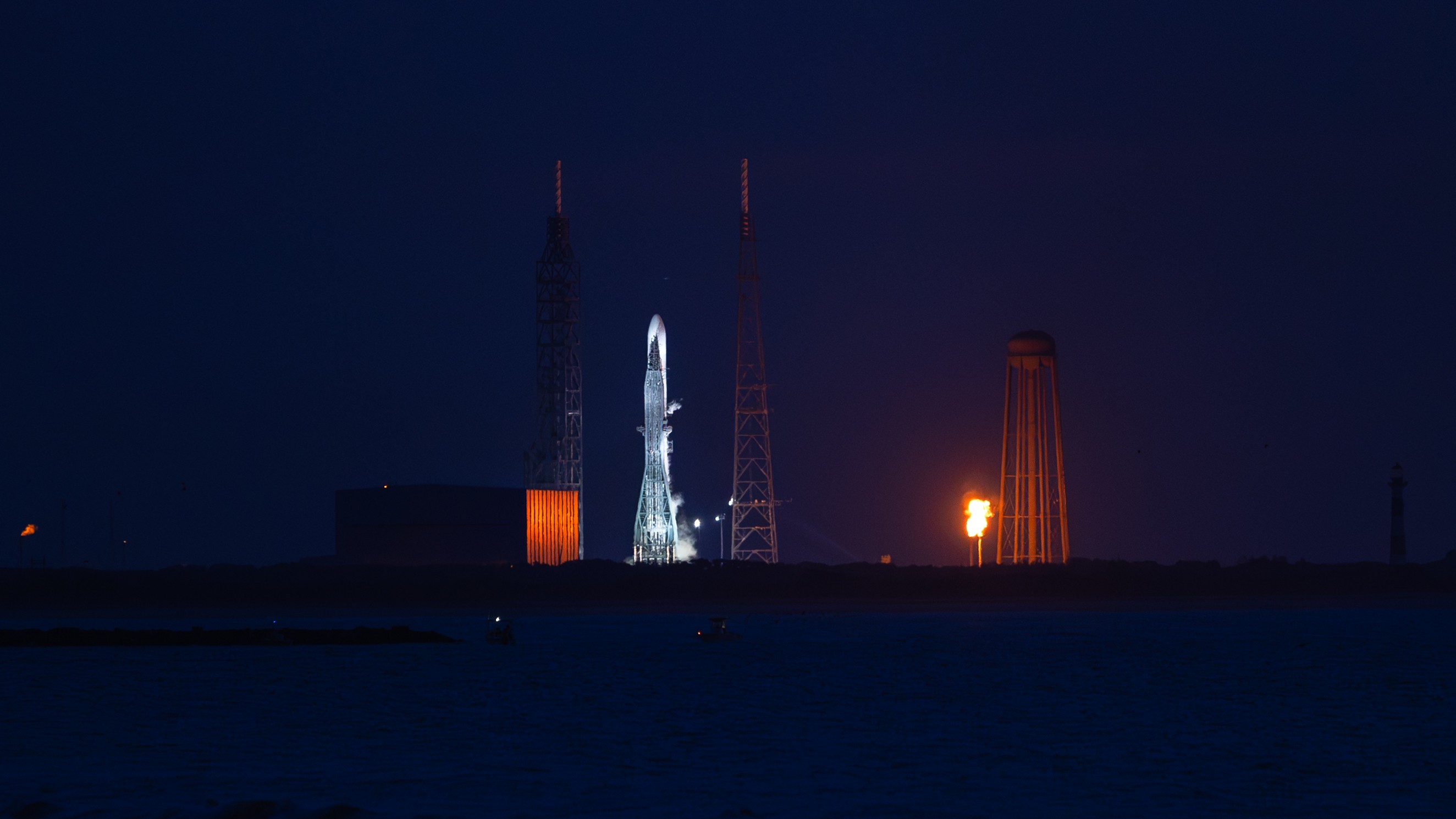 A rocket stands on a launch pad at night.