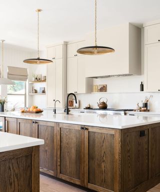 modern kitchen with wood island, white counters with neutral cabinets and brass pendant lights