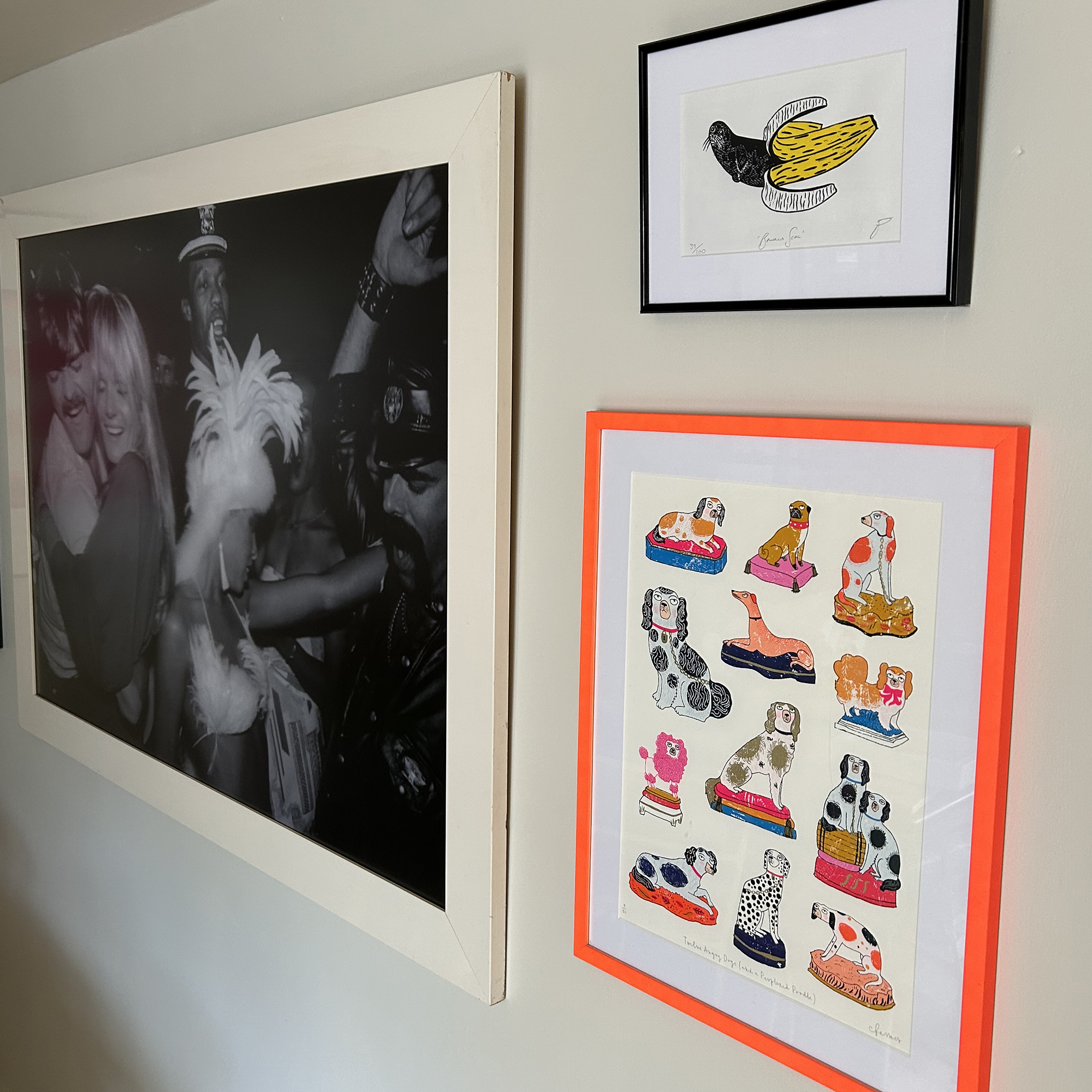 art on a white wall displayed in different coloured frames including bright orange
