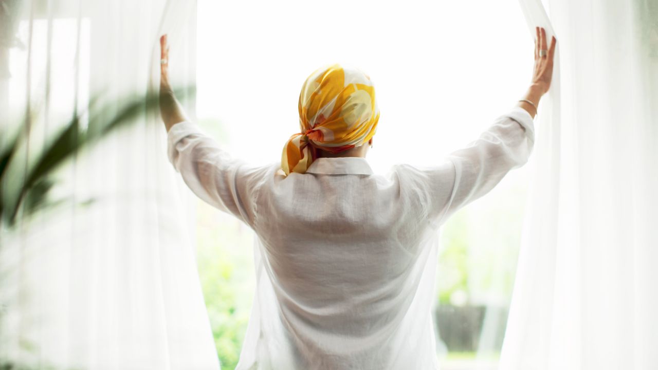 woman in headscarf looking out the window