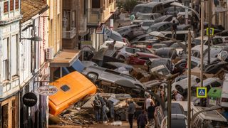 A pile of cars and debris covered in mood on a street in Valencia