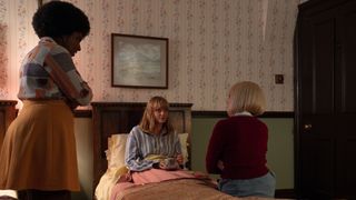 Joyce and Trixie stand by Rosalind's bed as she sits up drinking tea in her pyjamas