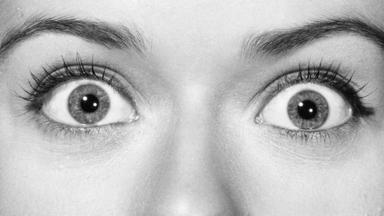 Extreme closeup of a woman&#039;s eyes, wide with shock.