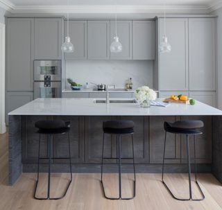 kitchen with grey cabinets white counter and black bar stools