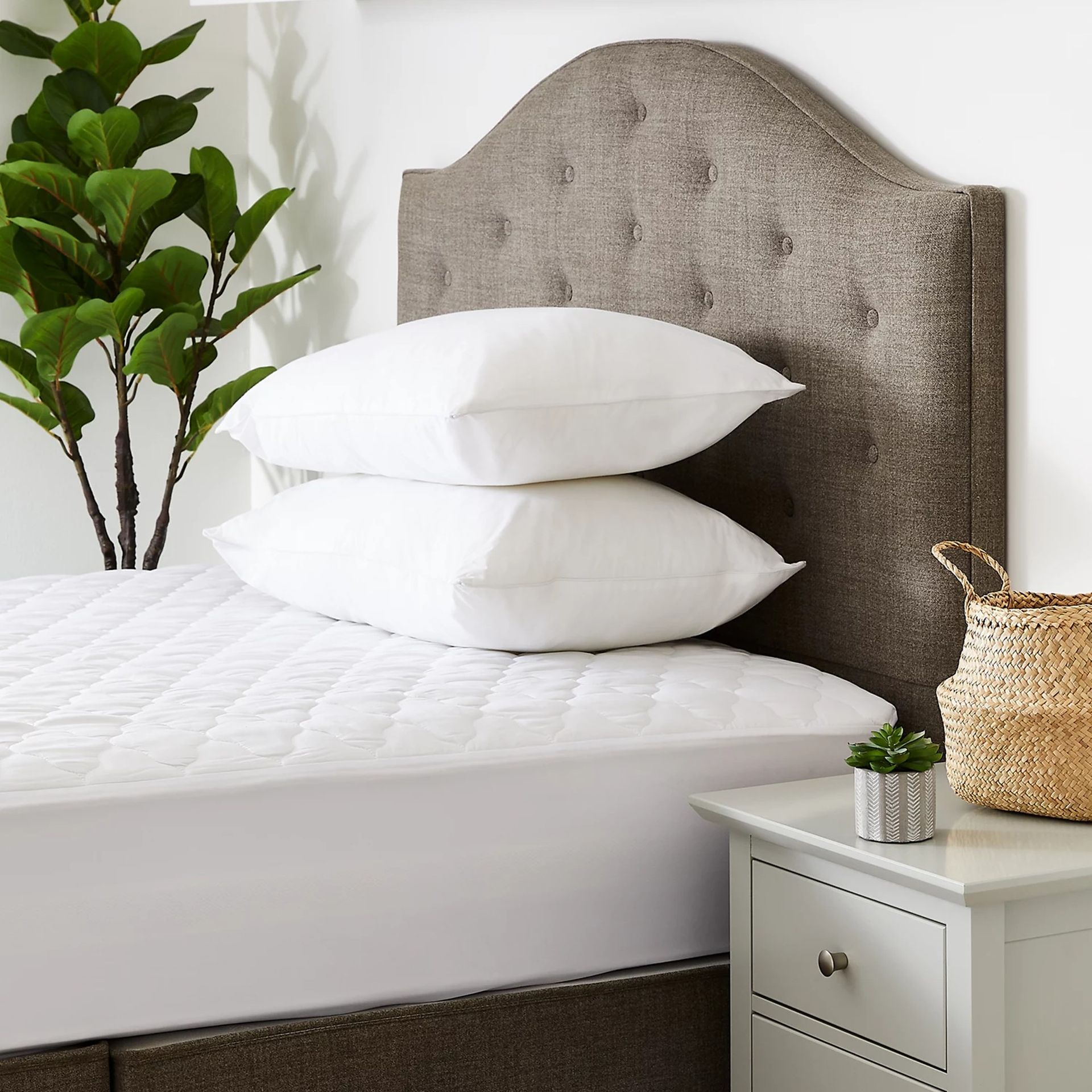 Marks & Spencer waterproof mattress protector on a be with an upholstered headboard