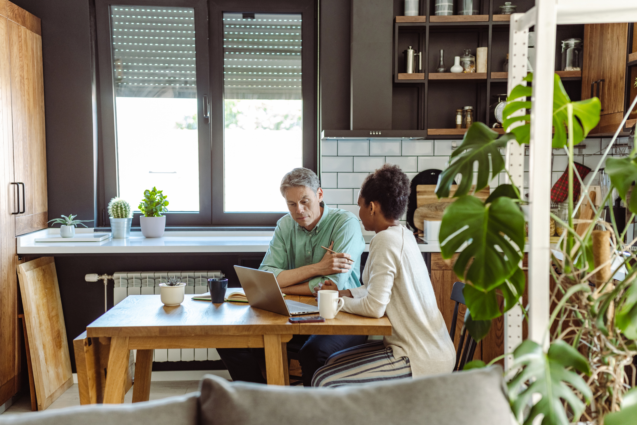 Multi-racial mature couplet home at the kitchen table discussing finances. 