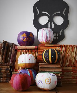 Painted pumpkins standing on pile of books