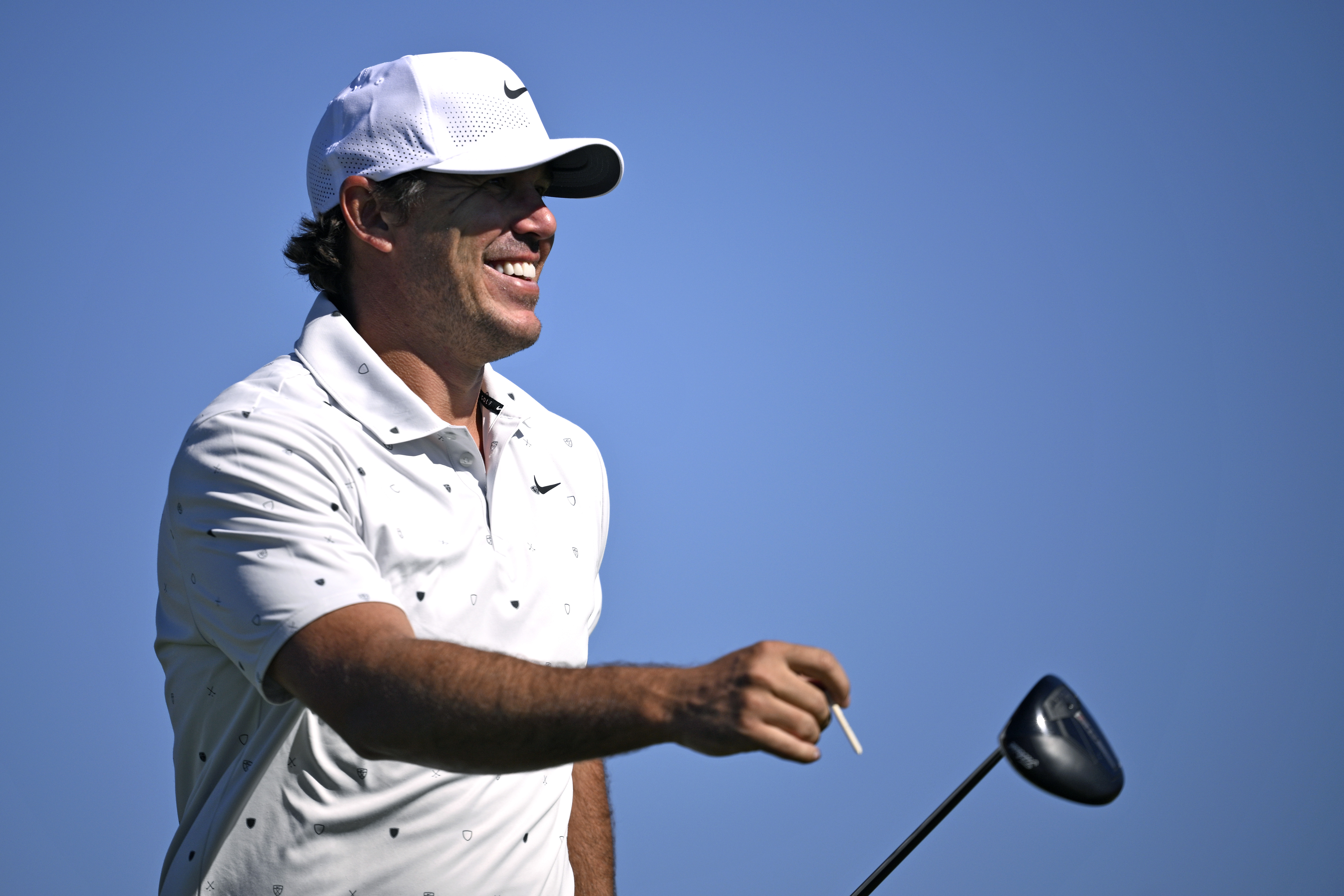 Brooks Koepka smiles and walks off the tee box