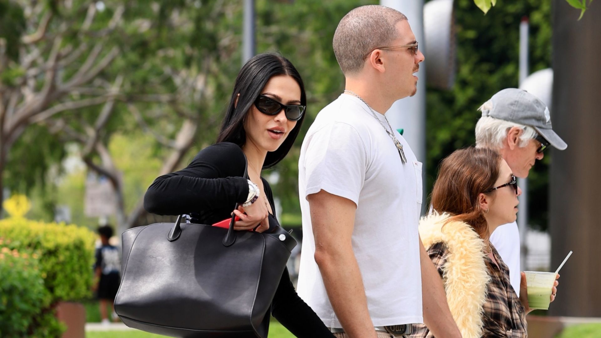 Amelia Grey Hamlin walks down the street wearing capri joggers with black ballet flats, a black long sleeve top and sunglasses.