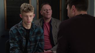 Dylan Wilson looks scared as Kit Green talks to him. Sean Tully sits behind Dylan with a worried expression on his face in Coronation Street.