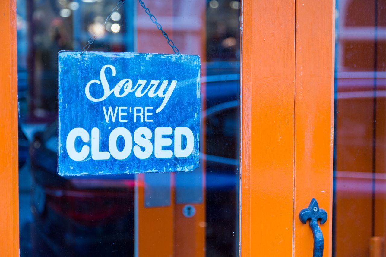 blue sign in store window saying sorry we&#039;re closed