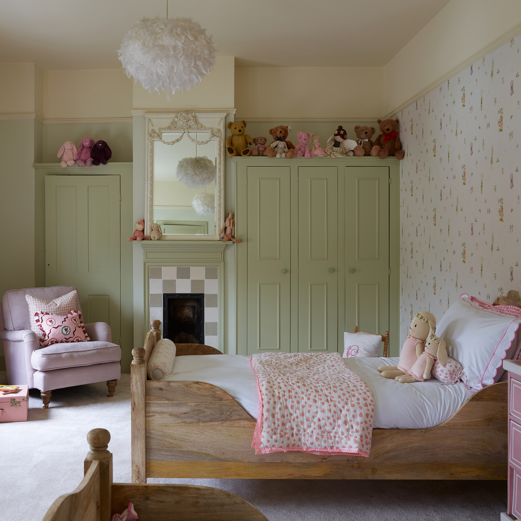 girl's bedroom with green painted fitted wardrobes, pink and green wallpaper, wooden sleigh beds and feather lampshade