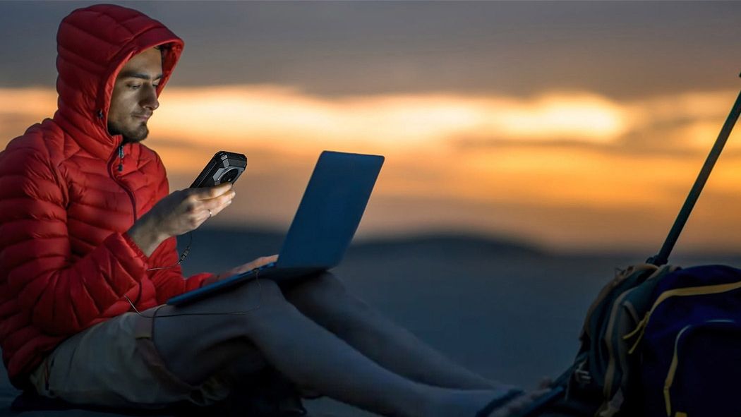 Picture of a man charging his laptop with a smartphone